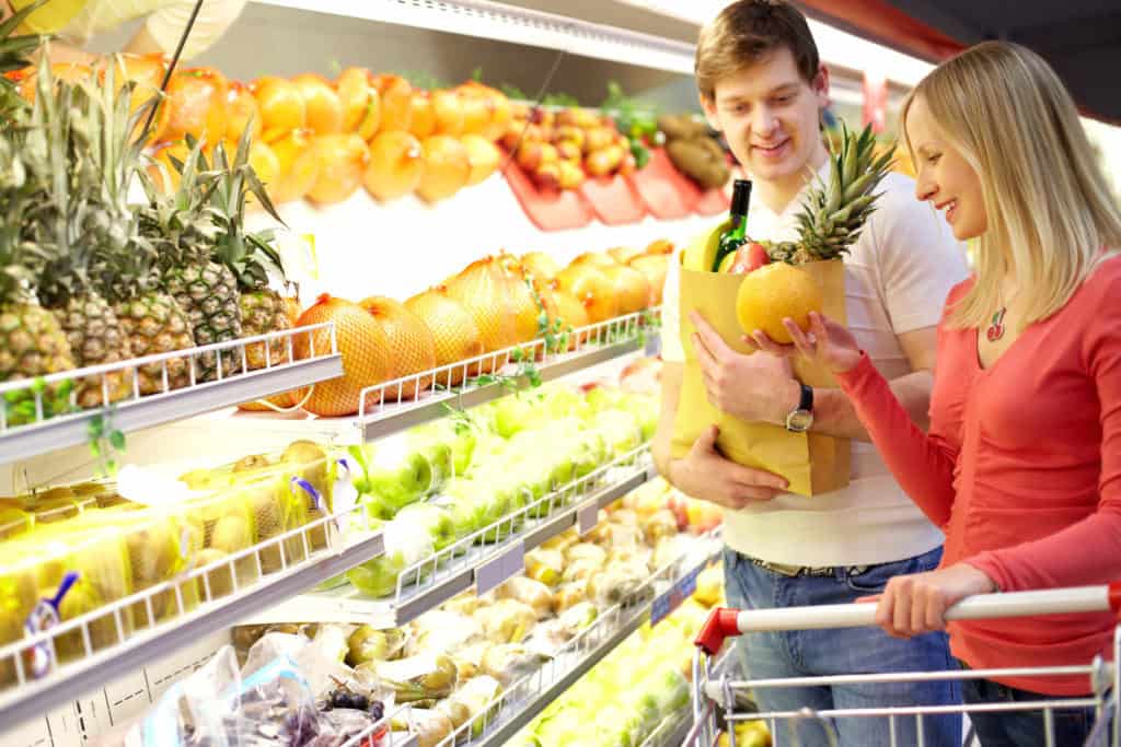 Ungt par køber frugt og grønt i supermarked